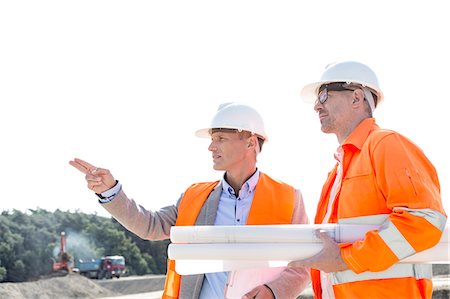 simsearch:632-07495018,k - Male engineers discussing at construction site against clear sky Photographie de stock - Premium Libres de Droits, Code: 693-08127785