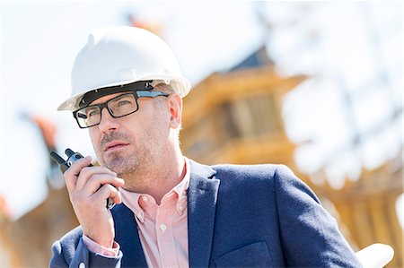 formal wear - Male supervisor using walkie-talkie at construction site Stock Photo - Premium Royalty-Free, Code: 693-08127801