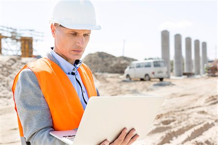 Supervisor using laptop at construction site on sunny day Stock Photo - Premium Royalty-Free, Code: 693-08127811
