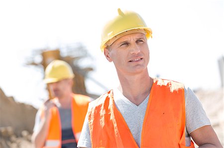 simsearch:693-08127789,k - Male worker at construction site with colleague standing in background Stock Photo - Premium Royalty-Free, Code: 693-08127822