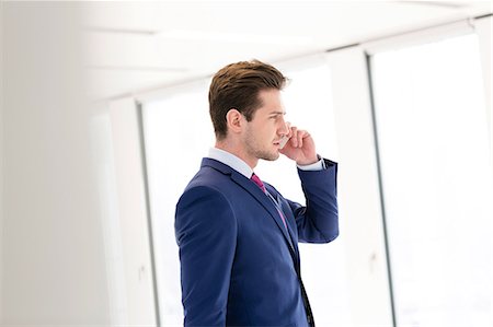 simsearch:693-08769289,k - Side view of young businessman using mobile phone in new office Stock Photo - Premium Royalty-Free, Code: 693-08769191