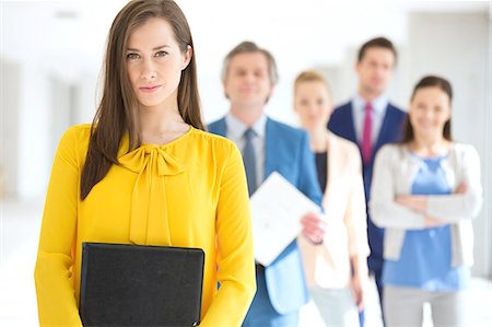 Portrait of confident young businesswoman with team in background at office Stock Photo - Premium Royalty-Free, Code: 693-08769249