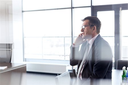 simsearch:693-08769320,k - Side view of mature businessman talking on mobile phone at office Stock Photo - Premium Royalty-Free, Code: 693-08769297