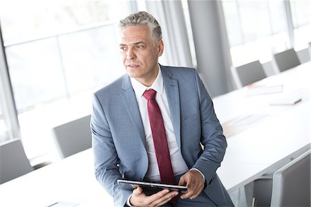 simsearch:693-07456224,k - Thoughtful mature businessman holding digital tablet while leaning on conference table Stock Photo - Premium Royalty-Free, Code: 693-08769291