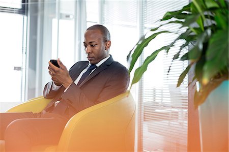 simsearch:693-08769289,k - Young businessman using mobile phone on chair in office Stock Photo - Premium Royalty-Free, Code: 693-08769342