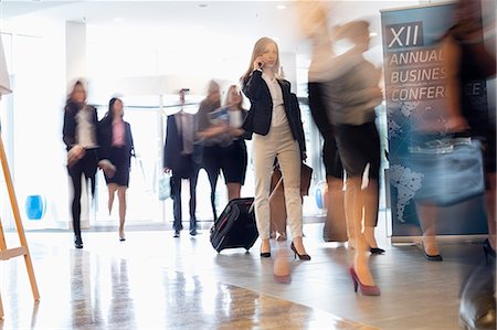 person talking on cell phone motion blur - Blurred motion of business people with luggage walking at convention center Stock Photo - Premium Royalty-Free, Code: 693-08769397