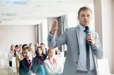 speaker and audience - Businessman speaking through microphone during seminar in convention center Foto de stock - Sin royalties Premium, Código: 693-08769417