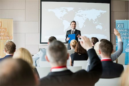 focus on background - Smiling public speaker asking questions to audience during seminar Stock Photo - Premium Royalty-Free, Code: 693-08769418