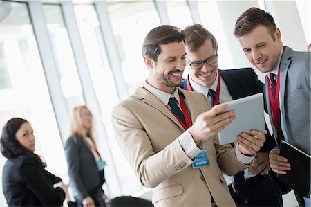 Businessmen using digital tablet at convention center Stock Photo - Premium Royalty-Free, Code: 693-08769464