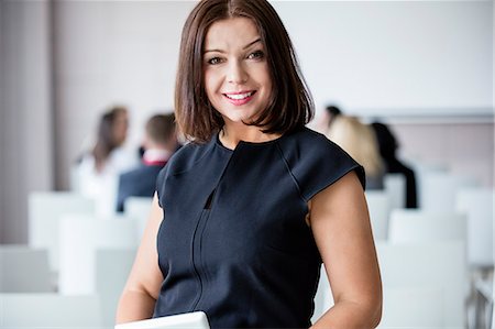 seminar not student not school not food not breakfast not lunch not dinner - Portrait of smiling businesswoman standing in seminar hall Stock Photo - Premium Royalty-Free, Code: 693-08769473