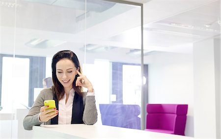 simsearch:693-08769593,k - Beautiful young businesswoman using mobile phone in office Stock Photo - Premium Royalty-Free, Code: 693-08769546