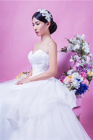 simsearch:6115-08101208,k - Elegant bride looking away while sitting on chair against pink background Stock Photo - Premium Royalty-Free, Code: 693-08769607