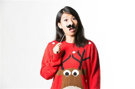 red happy - Portrait of woman in Christmas sweater standing with fake moustache Stock Photo - Premium Royalty-Free, Code: 693-08769603