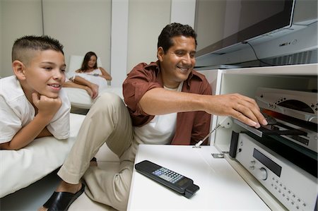 Father with son Putting Disc in DVD Player in living room Stock Photo - Premium Royalty-Free, Code: 693-03299392