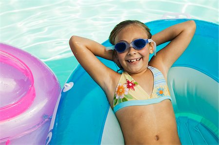 swimming pool with raft - Girl (7-9) lying on inflatable raft in swimming pool, view from above, portrait. Stock Photo - Premium Royalty-Free, Code: 693-03299414