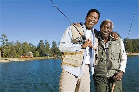 simsearch:693-06378940,k - Senior man and son holding fishing rods by lake, smiling, (portrait) Fotografie stock - Premium Royalty-Free, Codice: 693-03299585