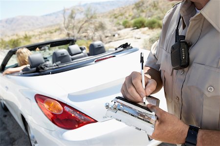 Police officer writing traffic ticket to woman sitting in car Fotografie stock - Premium Royalty-Free, Codice: 693-03299951