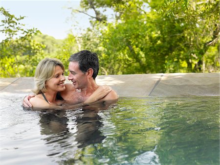 Adult couple embracing in pool, smiling Stock Photo - Premium Royalty-Free, Code: 693-03304041