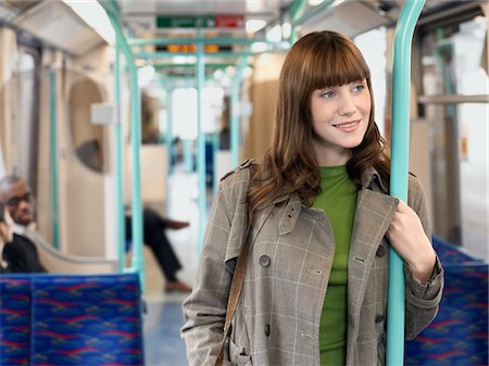 Smiling, Young Woman Standing on Commuter Train, holding bar Stock Photo - Premium Royalty-Free, Code: 693-03304106