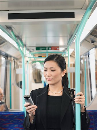 Businesswoman Using Cell Phone, holding onto bar on Train Stock Photo - Premium Royalty-Free, Code: 693-03304108