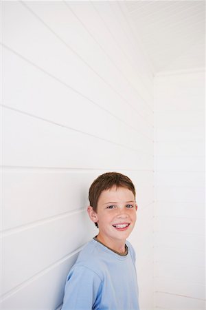 Young boy standing against weather boarded wall, portrait Stock Photo - Premium Royalty-Free, Code: 693-03304259