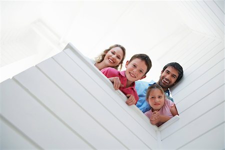 Family peering over white wall, view from below Stock Photo - Premium Royalty-Free, Code: 693-03304269