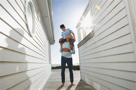 Grandfather giving grandson piggyback in passageway between houses Stock Photo - Premium Royalty-Free, Code: 693-03304281