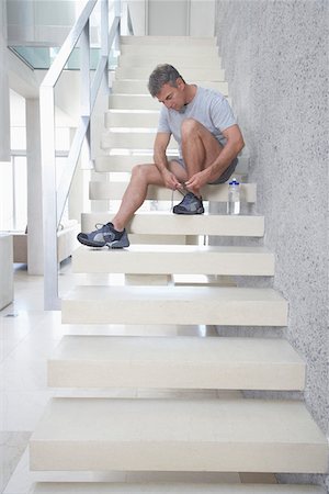 stair sports - Mid-adult man sitting on stairs, tying shoes Stock Photo - Premium Royalty-Free, Code: 693-03304375