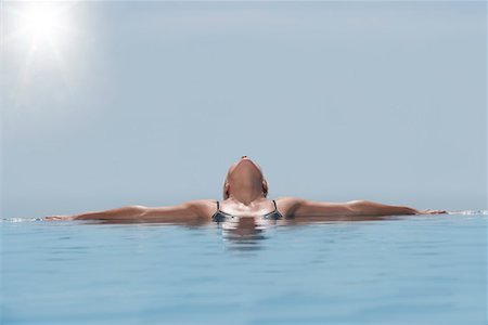 Woman lying, head back, sunbathing in pool Stock Photo - Premium Royalty-Free, Code: 693-03304373