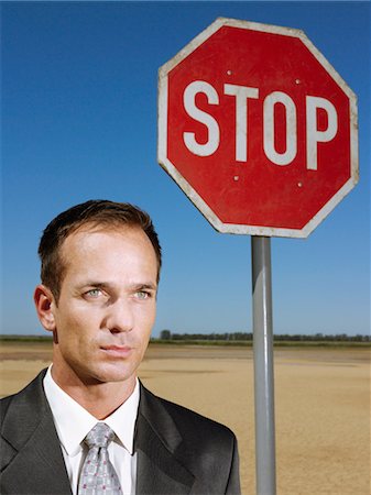 simsearch:693-03304499,k - Businessman standing next to stop sign in desert, head and shoulders Stock Photo - Premium Royalty-Free, Code: 693-03304484