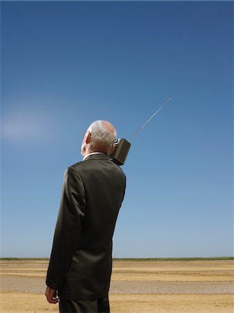 Businessman with radio on shoulder in desert, back view Foto de stock - Sin royalties Premium, Código: 693-03304495