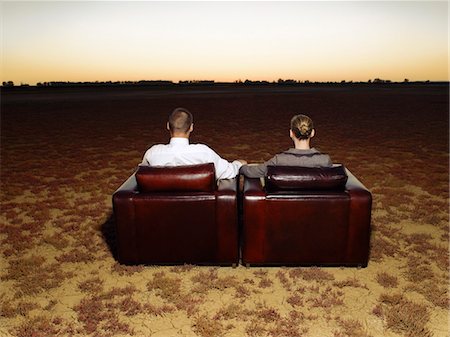 Couple watching sunset sitting in armchairs in open plain, back view Stock Photo - Premium Royalty-Free, Code: 693-03304514