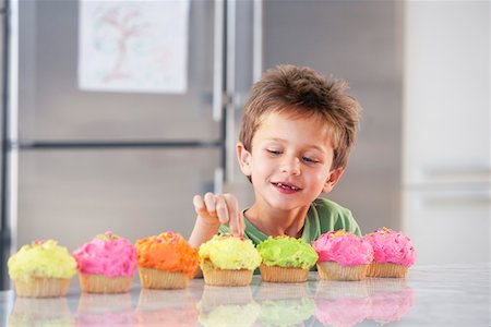 sneaking boy - Young boy picking decoration off cupcake in kitchen Stock Photo - Premium Royalty-Free, Code: 693-03304602