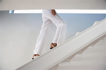 Woman walking up staircase indoors, low section Stock Photo - Premium Royalty-Free, Code: 693-03304620