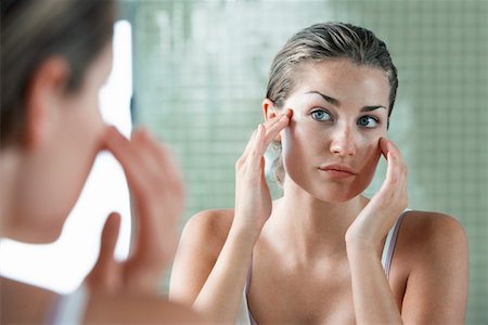 Woman rubbing temples in front of mirror Stock Photo - Premium Royalty-Free, Code: 693-03304833