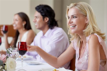 portrait of wedding party - Young woman in dress sitting at table of formal dinner party, laughing, side view Stock Photo - Premium Royalty-Free, Code: 693-03304908