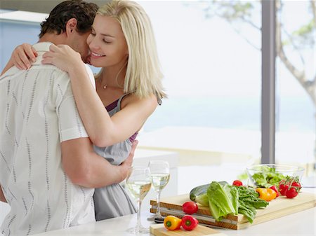 simsearch:693-03304937,k - Young couple hugging in kitchen near countertop with fresh produce and wineglasses Foto de stock - Sin royalties Premium, Código: 693-03304914