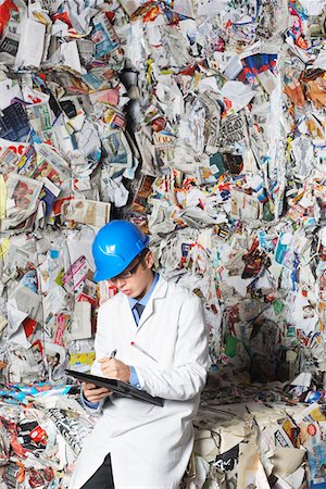 recycled paper industrial plant - Worker holding clipboard sitting on stacks of recycled paper, portrait Stock Photo - Premium Royalty-Free, Code: 693-03305013