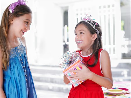 Two girls (7-9, 10-12) at birthday party, one holding present, smiling Stock Photo - Premium Royalty-Free, Code: 693-03305599