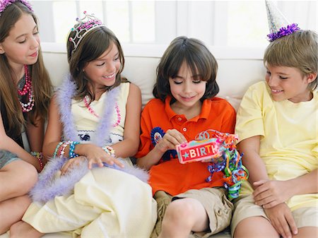 simsearch:693-03309303,k - Four children (7-12) sitting on sofa at birthday party, one opening present Stock Photo - Premium Royalty-Free, Code: 693-03305655