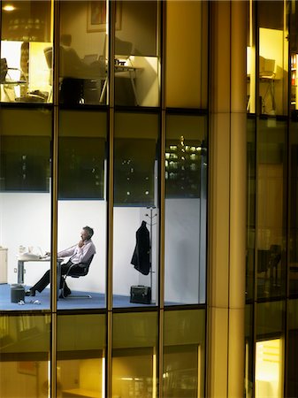 Homme d'affaires travaillant au comptoir dans le bureau, vue depuis l'extérieur de la construction Photographie de stock - Premium Libres de Droits, Code: 693-03305966