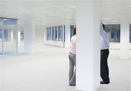 Two office workers talking behind column in empty office space Stock Photo - Premium Royalty-Free, Code: 693-03306042