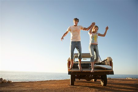 pick up truck and man - Young couple jumping from back of van parked by ocean Stock Photo - Premium Royalty-Free, Code: 693-03306146