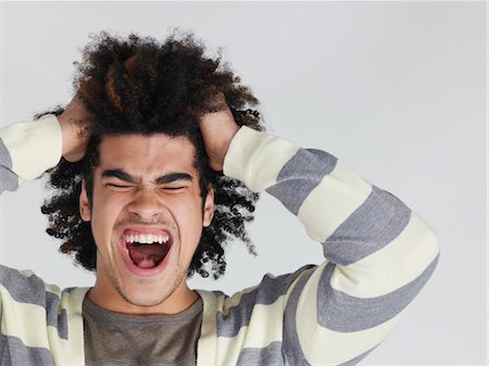 Young man with head in hands screaming Stock Photo - Premium Royalty-Free, Code: 693-03306838