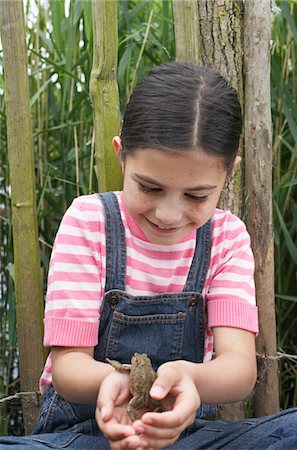 Girl (5-6) holding toad by fence Stock Photo - Premium Royalty-Free, Code: 693-03306949
