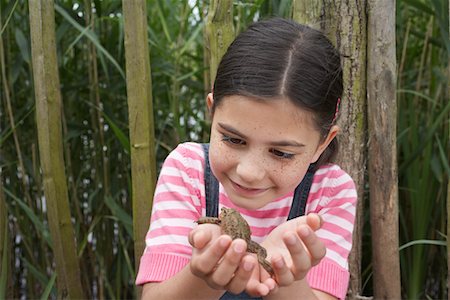 Girl (5-6) holding toad by fence Stock Photo - Premium Royalty-Free, Code: 693-03306951