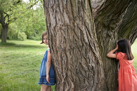 Two girls (7-9) playing hide and seek by tree Stock Photo - Premium Royalty-Free, Code: 693-03306971