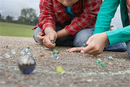Children (7-9) playing marbles, lying in playground Stock Photo - Premium Royalty-Free, Code: 693-03307000