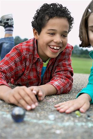 Boy and girl (7-9) playing marbles in playground Stock Photo - Premium Royalty-Free, Code: 693-03307001