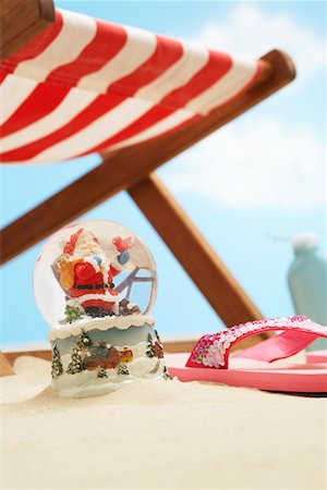 snowglobe - Souvenir santa snow globe under deckchair on beach, close up Stock Photo - Premium Royalty-Free, Code: 693-03307038